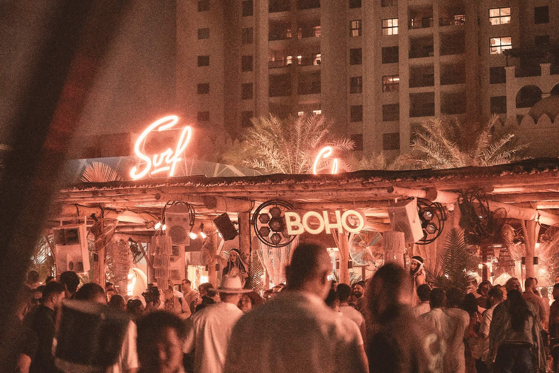 Nightlife crowd at Surf Club Dubai under warm neon lighting.